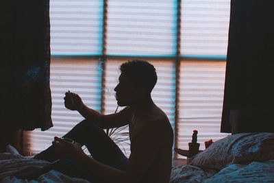 Silhouette man sitting on bed at home