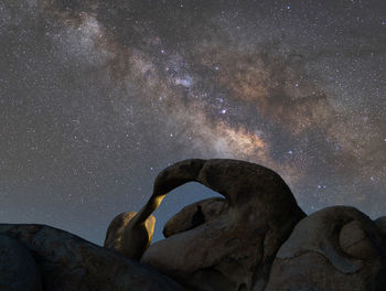 Milky way over mobius arch with a lone man sitting in the arch