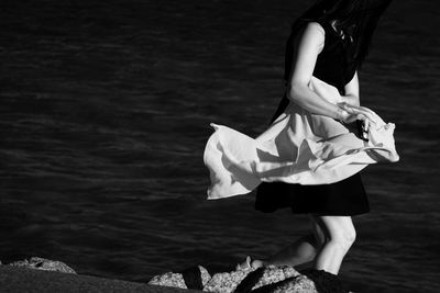 Woman standing on rock by sea