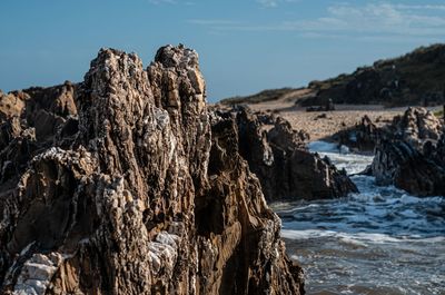Rock formation on beach against sky