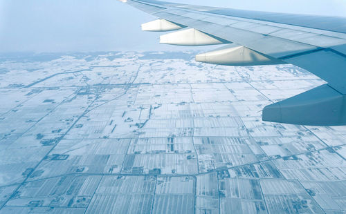 Cropped image of airplane flying over snow covered field