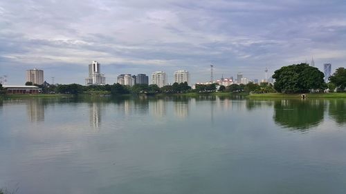 Scenic view of lake and cityscape against sky