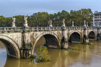 Arch bridge over river against sky