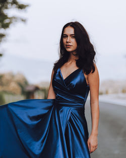 Young woman in blue dress standing on road