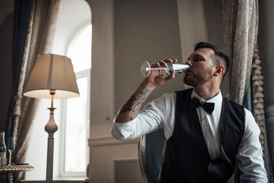 Full length of young man drinking glass