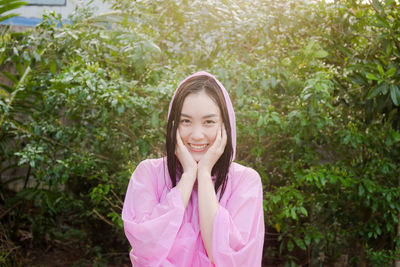 Portrait of smiling young woman with wet hair standing against plants