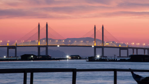 Penang bridge over selatan strait against sky during sunset