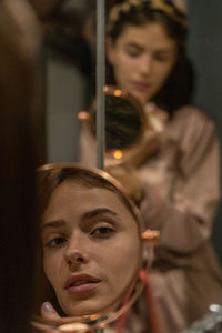 Portrait of young woman looking on mirror reflection