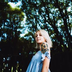 Portrait of smiling young woman standing against trees