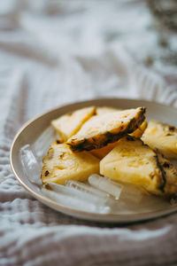 Close-up of pineapple slices and ice in plate on bed