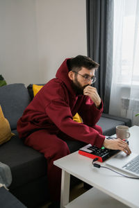 Young man using mobile phone while sitting on sofa at home