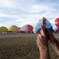 Close-up of hand holding camera against clear sky