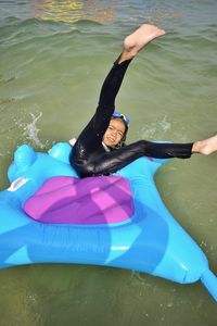 High angle view of girl lying on inflatable raft over lake