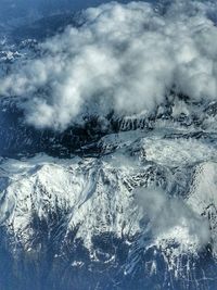 Snow covered landscape against cloudy sky