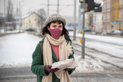 Portrait of young woman standing on snow in city