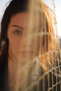 Close-up portrait of young woman seen through net