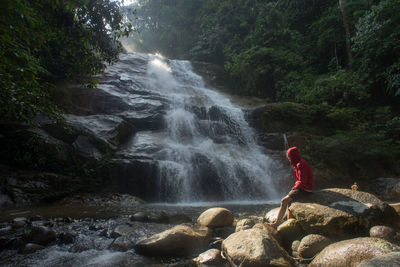 A male traveller exploring the beautiful of rainforest waterfall. 