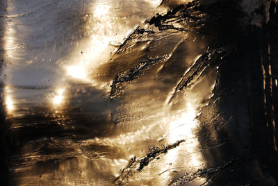 Close-up of wet beach against sky during sunset