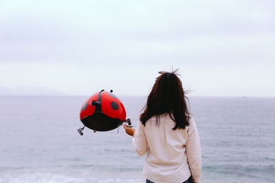 Woman holding balloon on beach