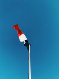 Low angle view of flag against clear blue sky