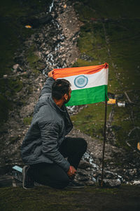 Rear view of man raising a flag