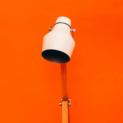 Low angle view of electric lamp against orange wall