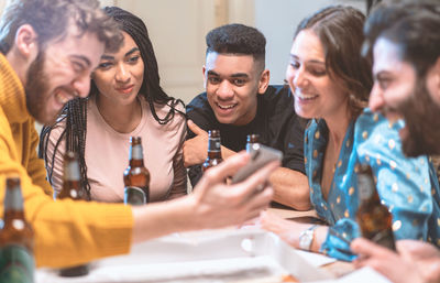 Group of people on table having fun watching video movies on the smartphone screen