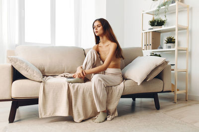 Young woman sitting on sofa at home