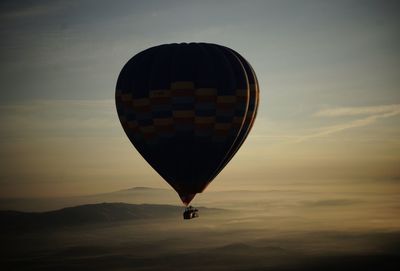 Hot air balloon flying against sky during sunset