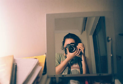 Portrait of man photographing camera at home