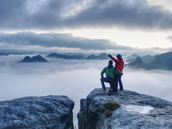 Rear view of people on rock against sky