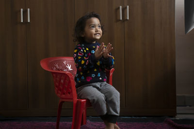 Portrait of smiling girl holding while standing on seat