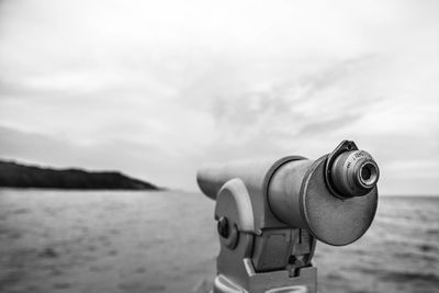 Close-up of coin-operated binoculars on beach against sky