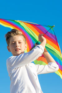 A boy of 8-9 years old happily launches a kite into the sky.
