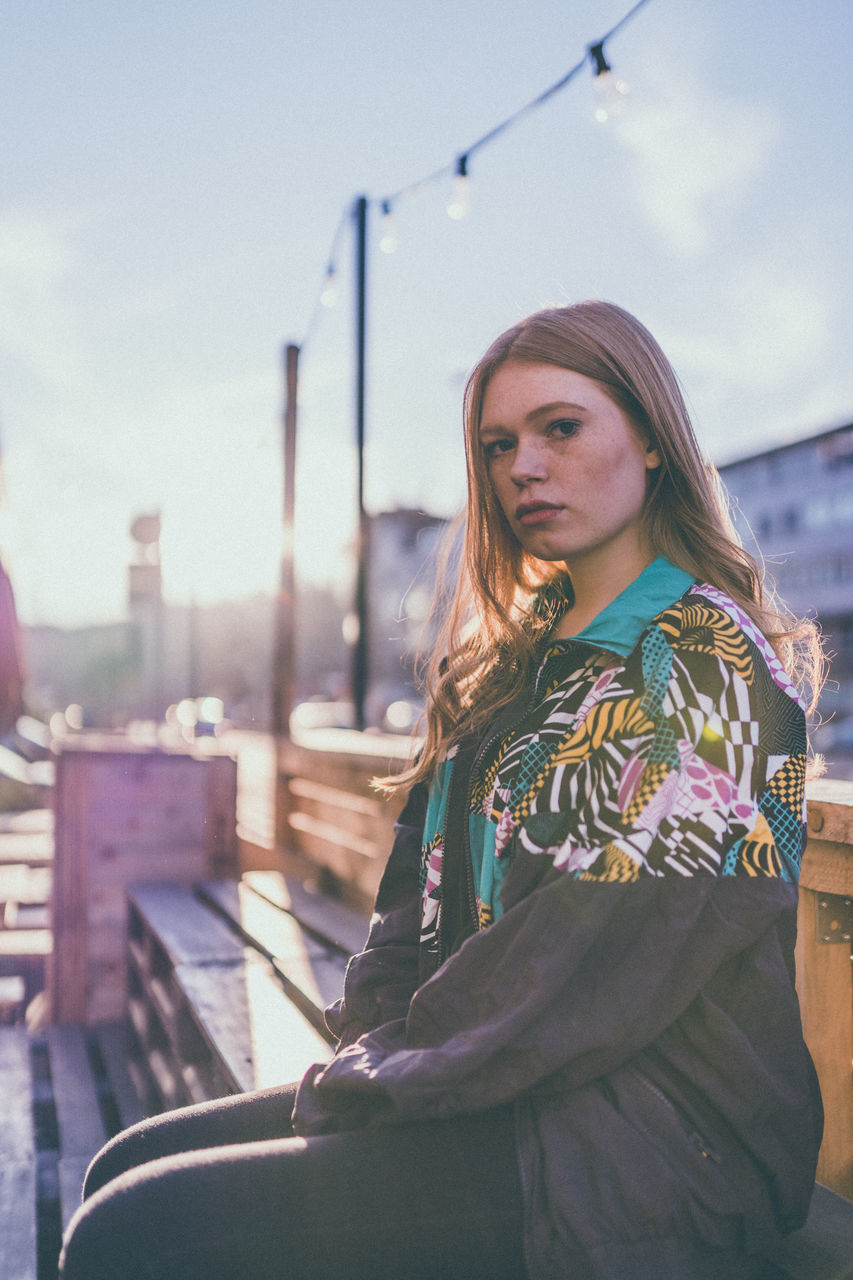 one person, young adult, real people, young women, leisure activity, lifestyles, casual clothing, three quarter length, architecture, sky, beauty, waist up, standing, day, focus on foreground, looking, looking away, nature, beautiful woman, hair, hairstyle, contemplation, outdoors, warm clothing