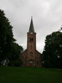 Low angle view of trees and building against sky