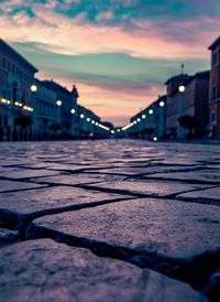 Surface level of street against sky at sunset