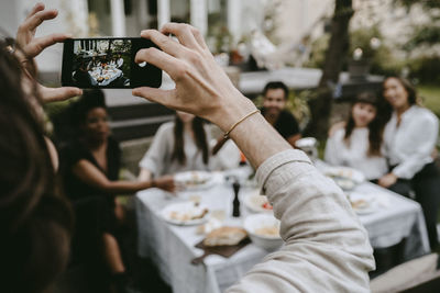 Midsection of woman photographing through mobile phone