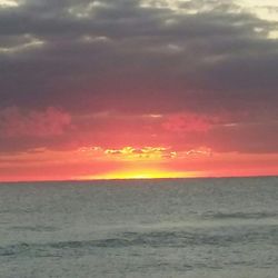 Scenic view of sea against cloudy sky at sunset