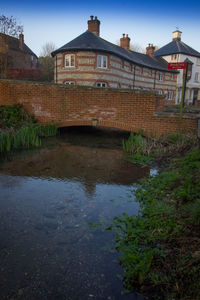 Bridge over river by buildings against sky