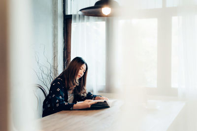 Young woman using phone while sitting at home