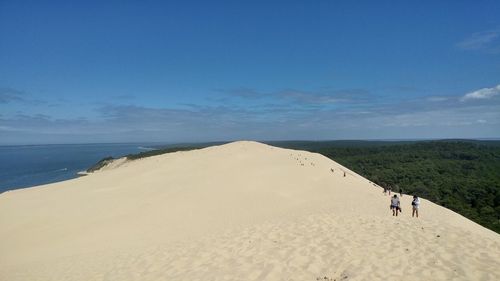 People walking at beach against sky