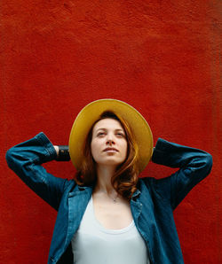 Portrait of young woman standing against yellow background