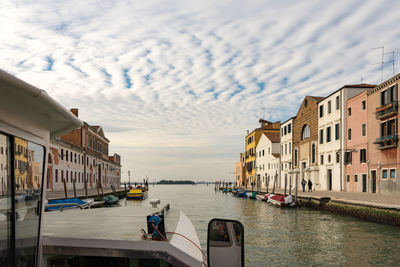 Canal amidst buildings in city against sky