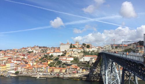 Bridge over river amidst buildings in city against sky