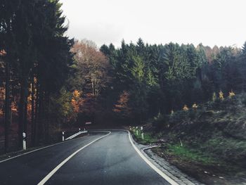 Road amidst trees against clear sky