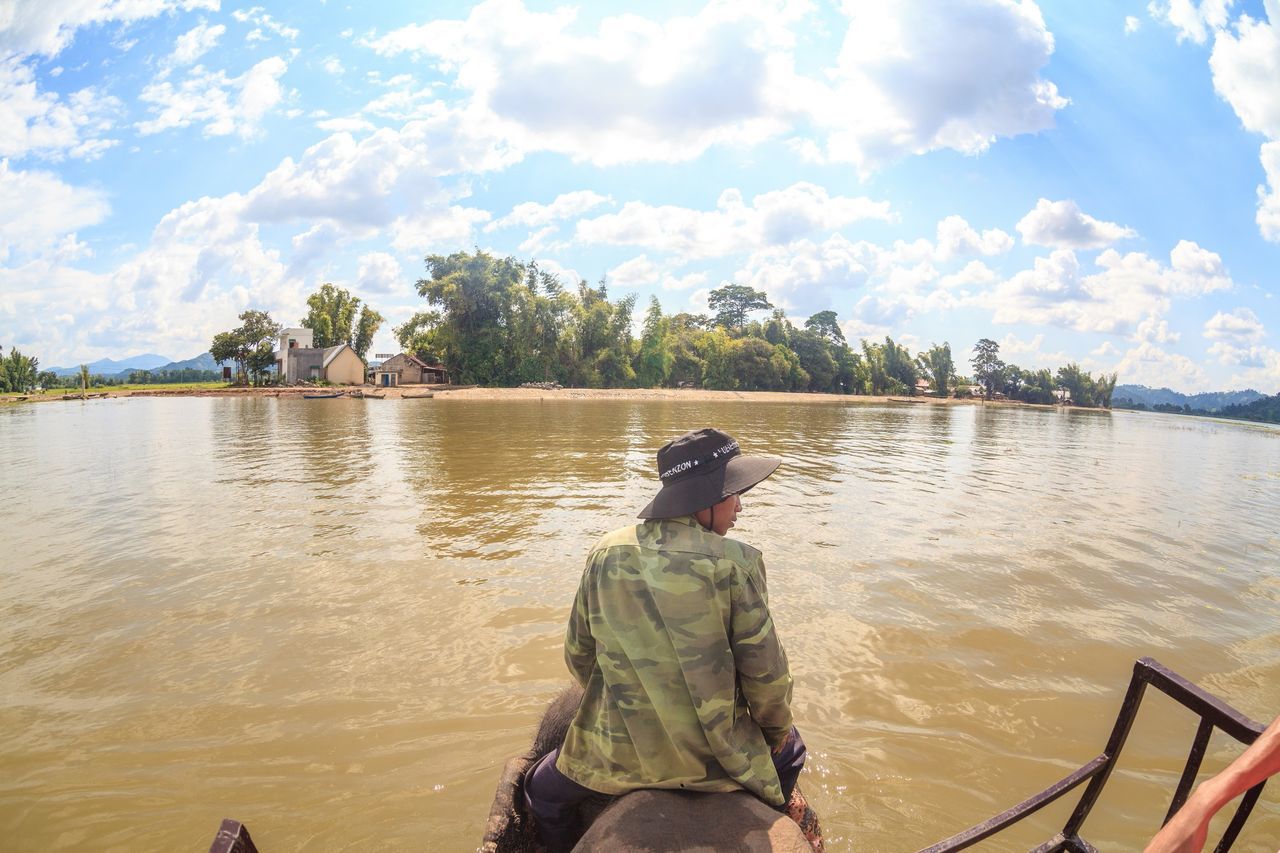 water, lifestyles, men, sky, leisure activity, rear view, lake, nautical vessel, cloud - sky, standing, nature, fishing, transportation, tranquility, sitting, mode of transport, boat, casual clothing