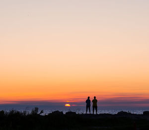 Silhouette of people on beach at sunset