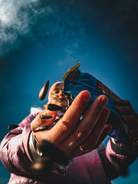 Midsection of man holding sunglasses against sky