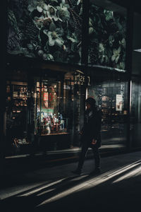 Side view of man walking on illuminated street at night